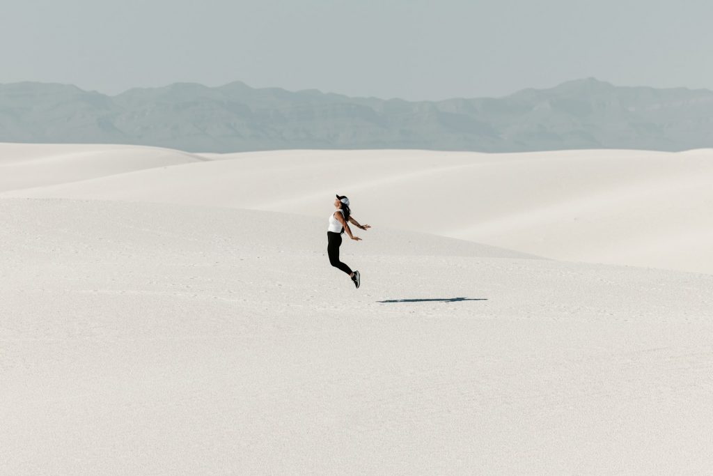 Woman jumping in vast white desert landscape